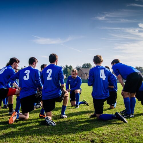 Group of young athletes in blue jerseys gathered in field