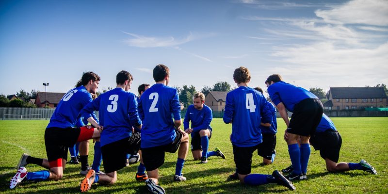 Group of young athletes in blue jerseys gathered in field