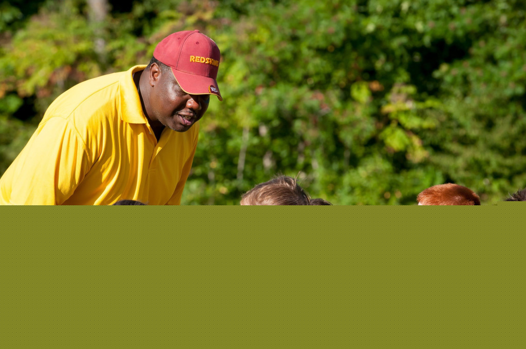 Coach talking to group of young athletes in maroon jerseys
