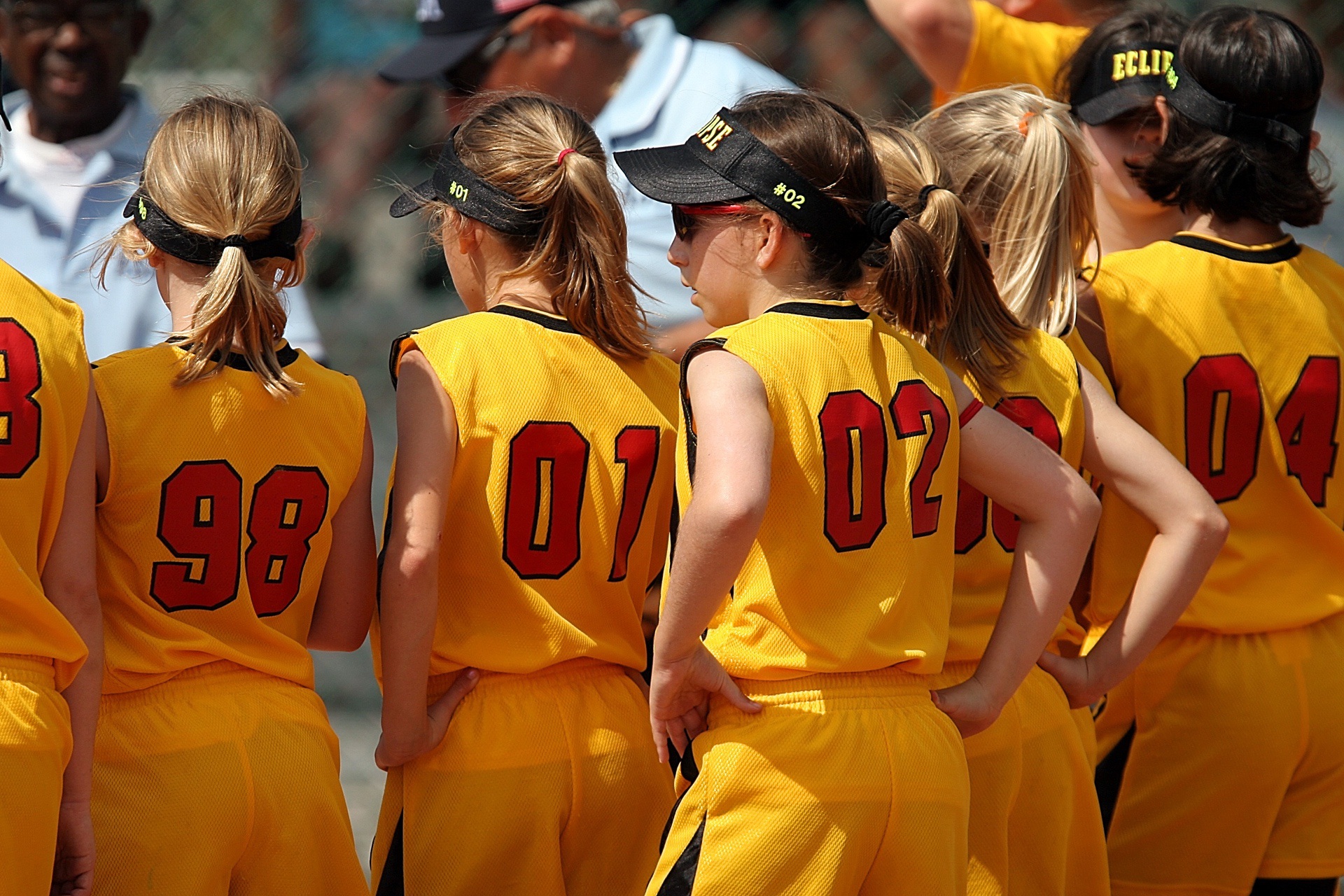 Group of young athletes wearing yellow uniforms with red numbers