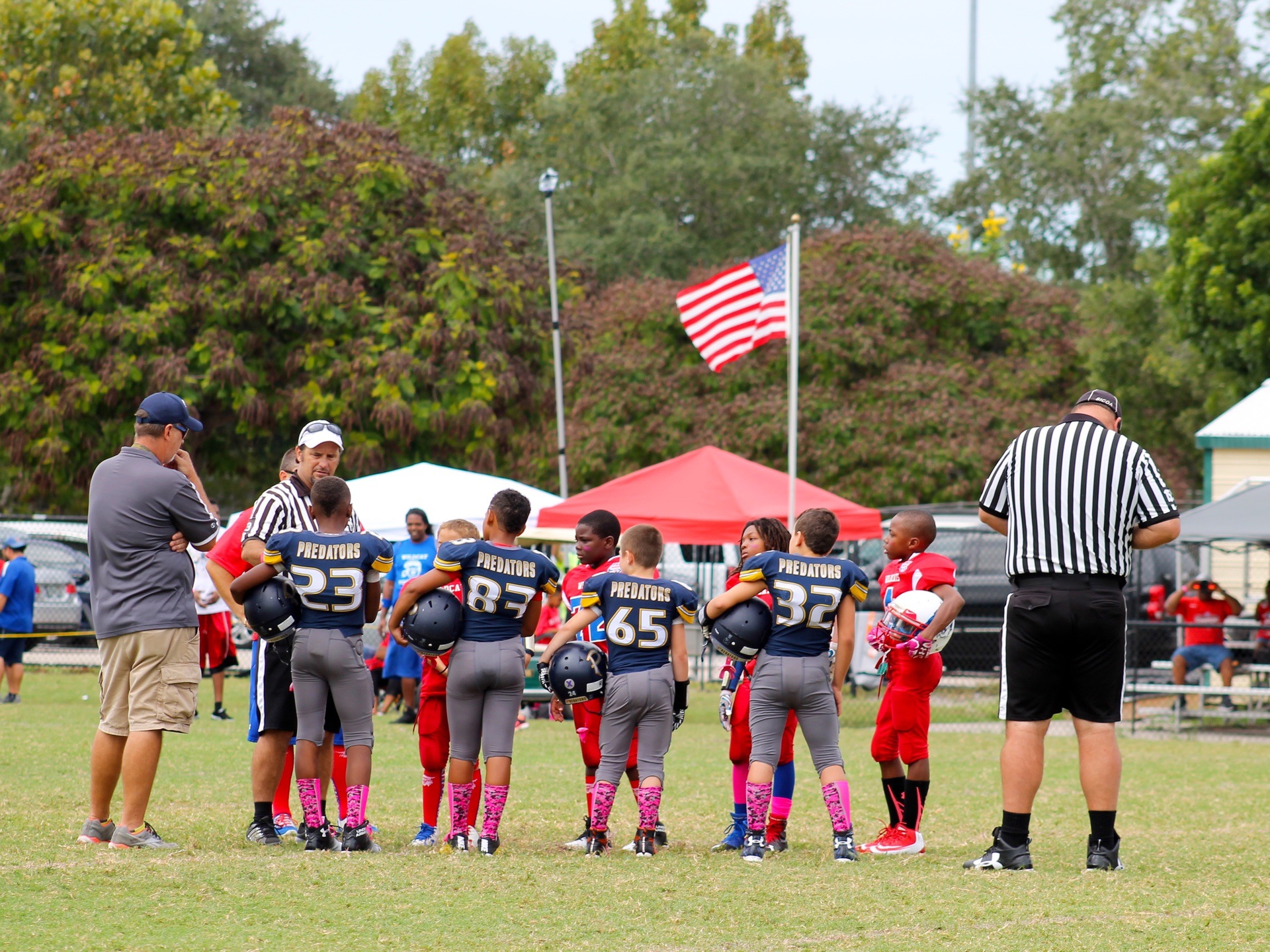 Referees and a coach standing near two uniformed teams during athletic event