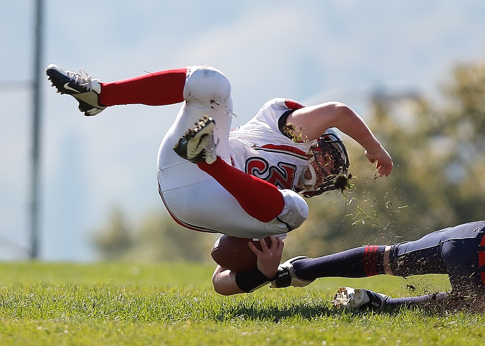 Young Football Athlete Falling on Grass
