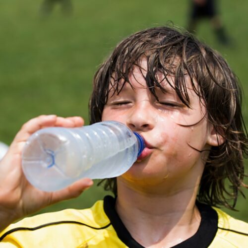 Young soccer athlete sweating and drinking water