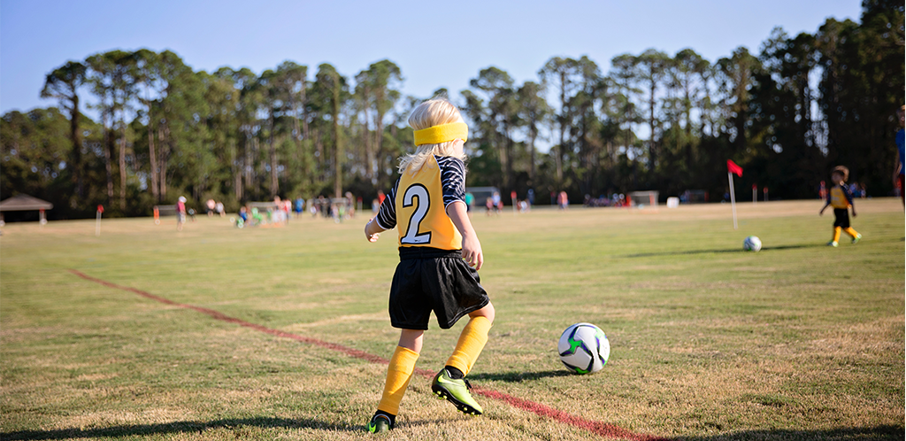 boy playing soccer in green soccer cleats