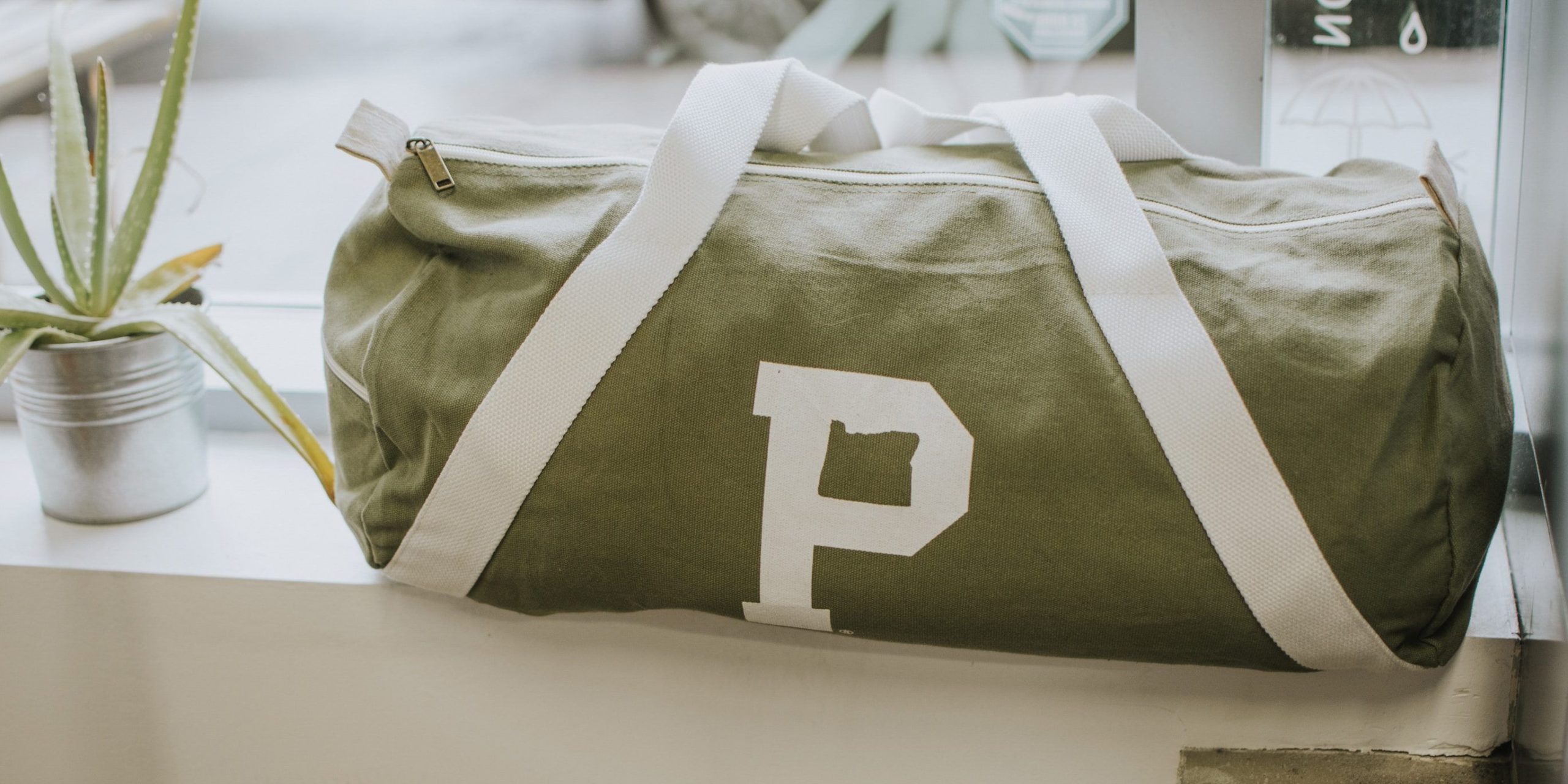 A view of a green canvas duffel bag next to an aloe plant
