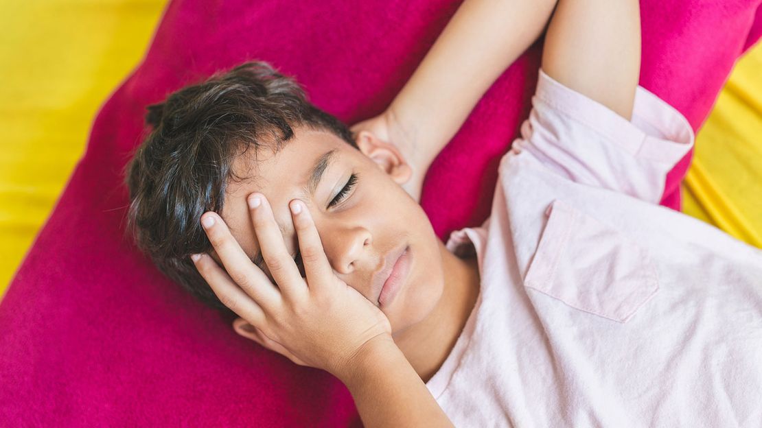 Child with concussion holding head and lying on mat