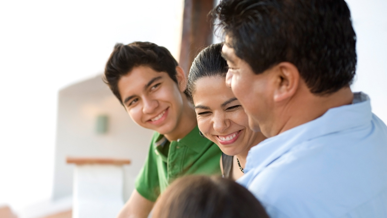 Teenager smiling next to happy mother and father