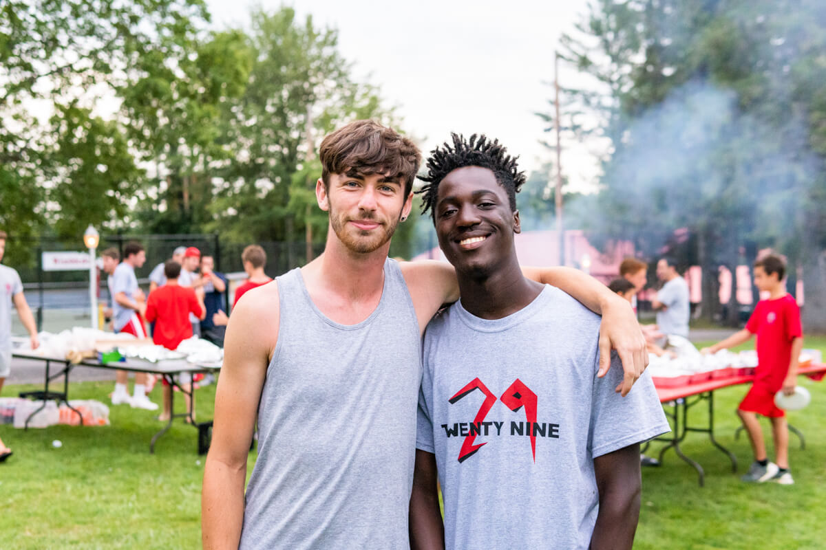 Camp counsellors posing for photo in front of outdoor cookout
