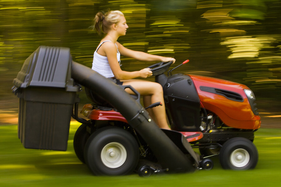 Teenager on riding mower cutting grass in warm weather