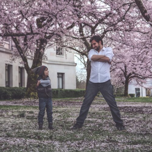 Father and son standing in field surrounded by cherry blossoms