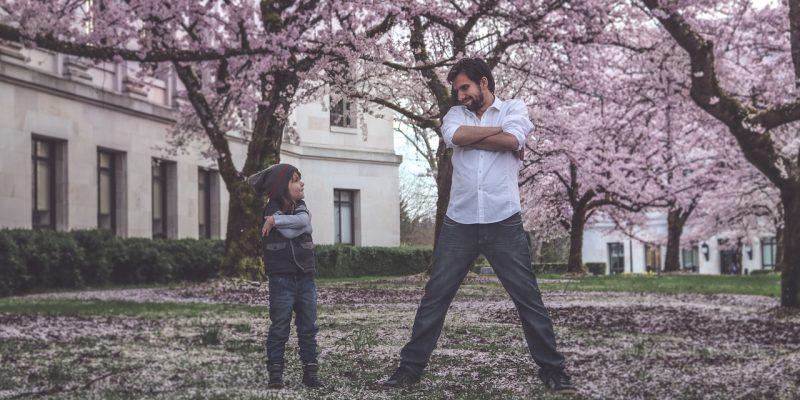 Father and son standing in field surrounded by cherry blossoms