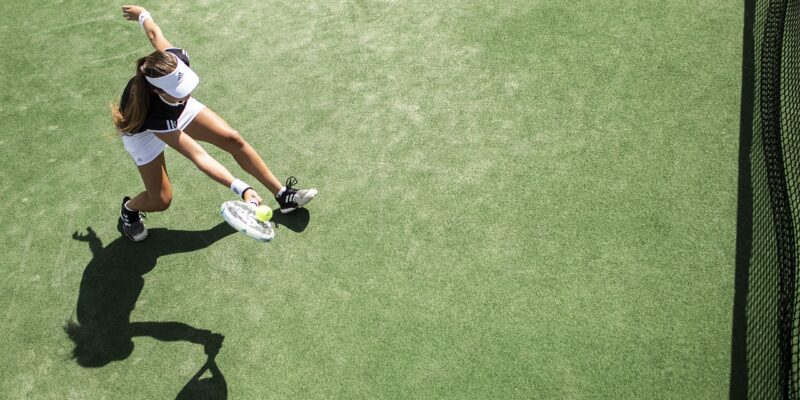 Teenager playing tennis on green court
