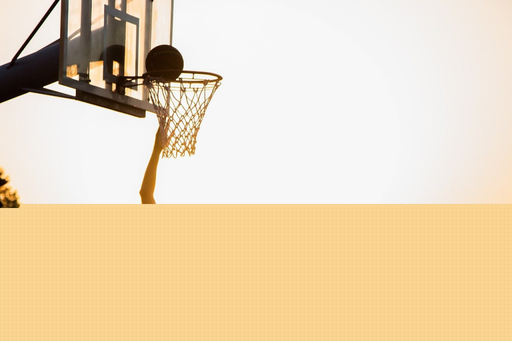 Teenager playing basketball at sunset
