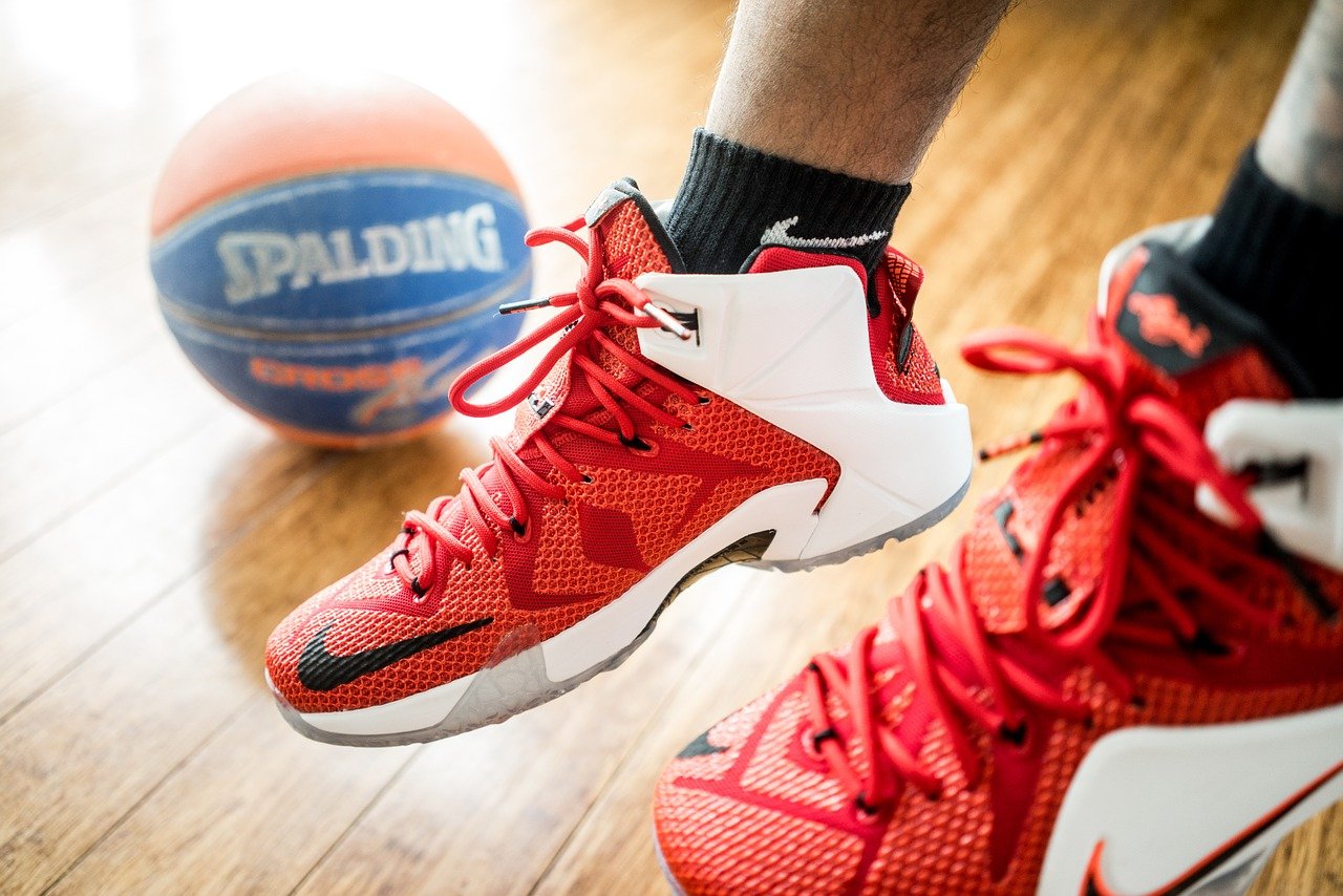 Close up of red sports sneakers near basketball on floor