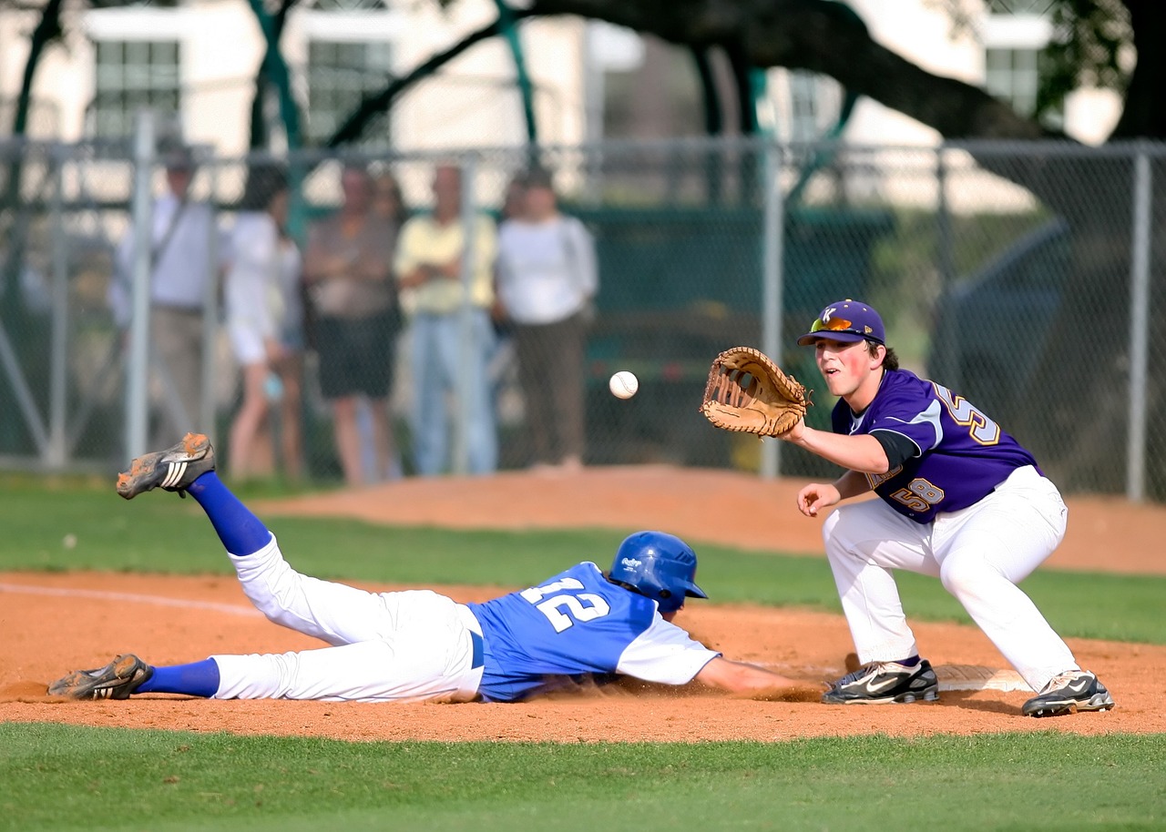 Baseball player catching ball as another player slides home during game