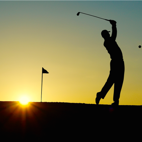 Silhouette of man playing golf at sunset on course