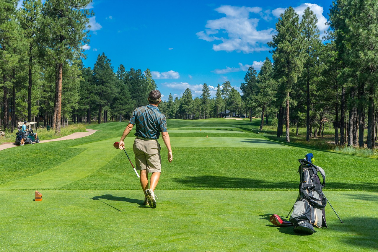 Man with clubs looking down fairway on golf course