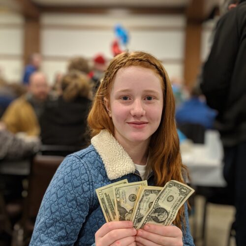 Young person holding dollar bills in hands after fundraising event
