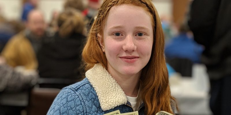 Young person holding dollar bills in hands after fundraising event