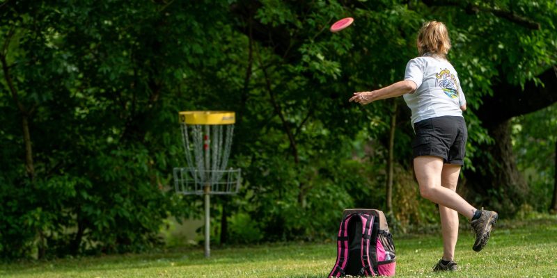 Parent playing disc golf in field