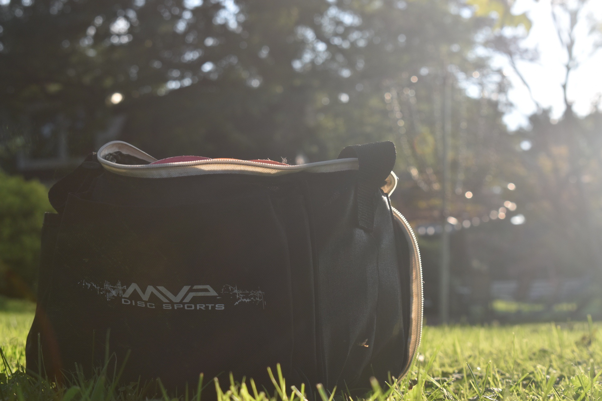 Bag of equipment for disc golf on grassy field