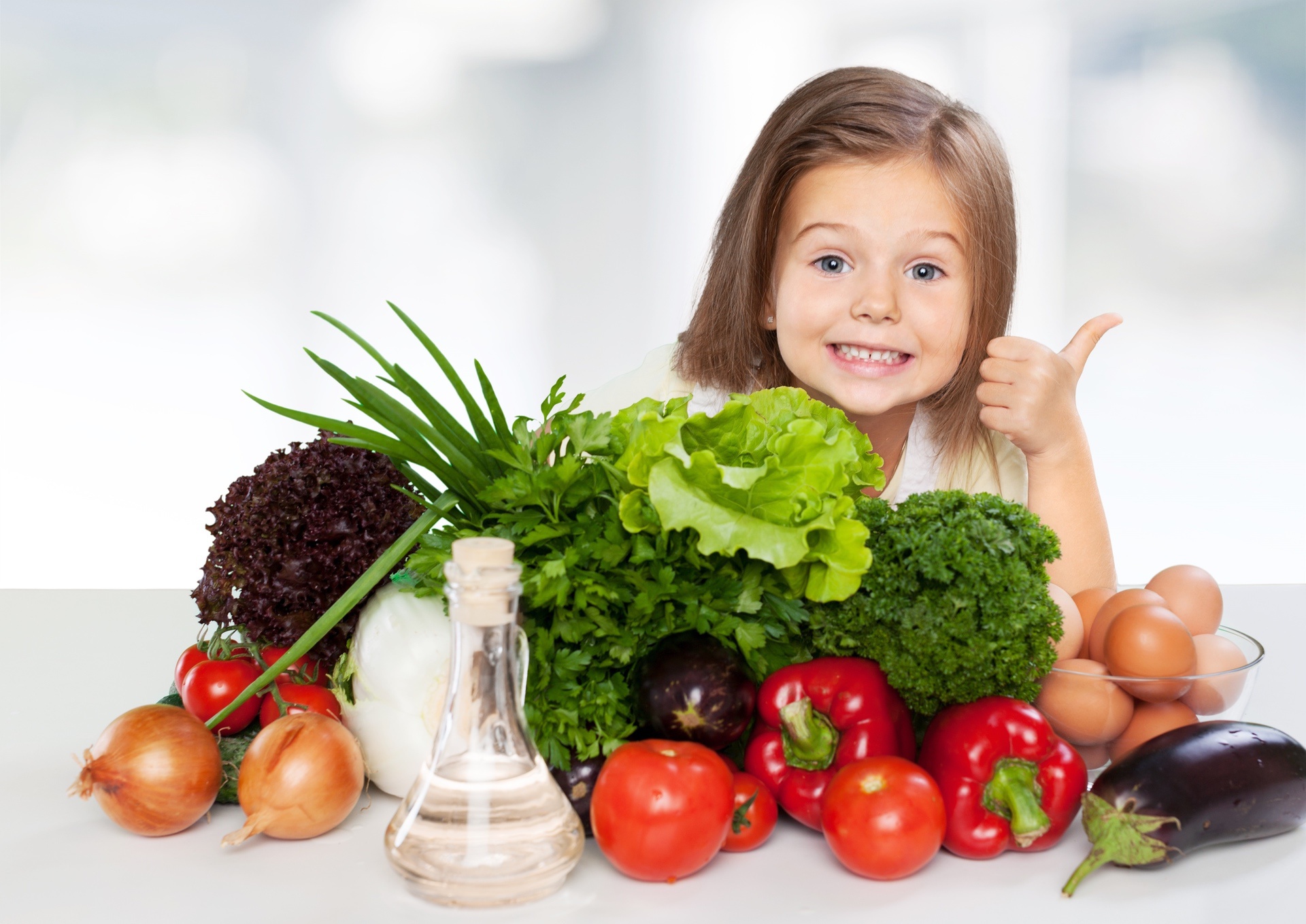 Girl smiling near a table of vegetables