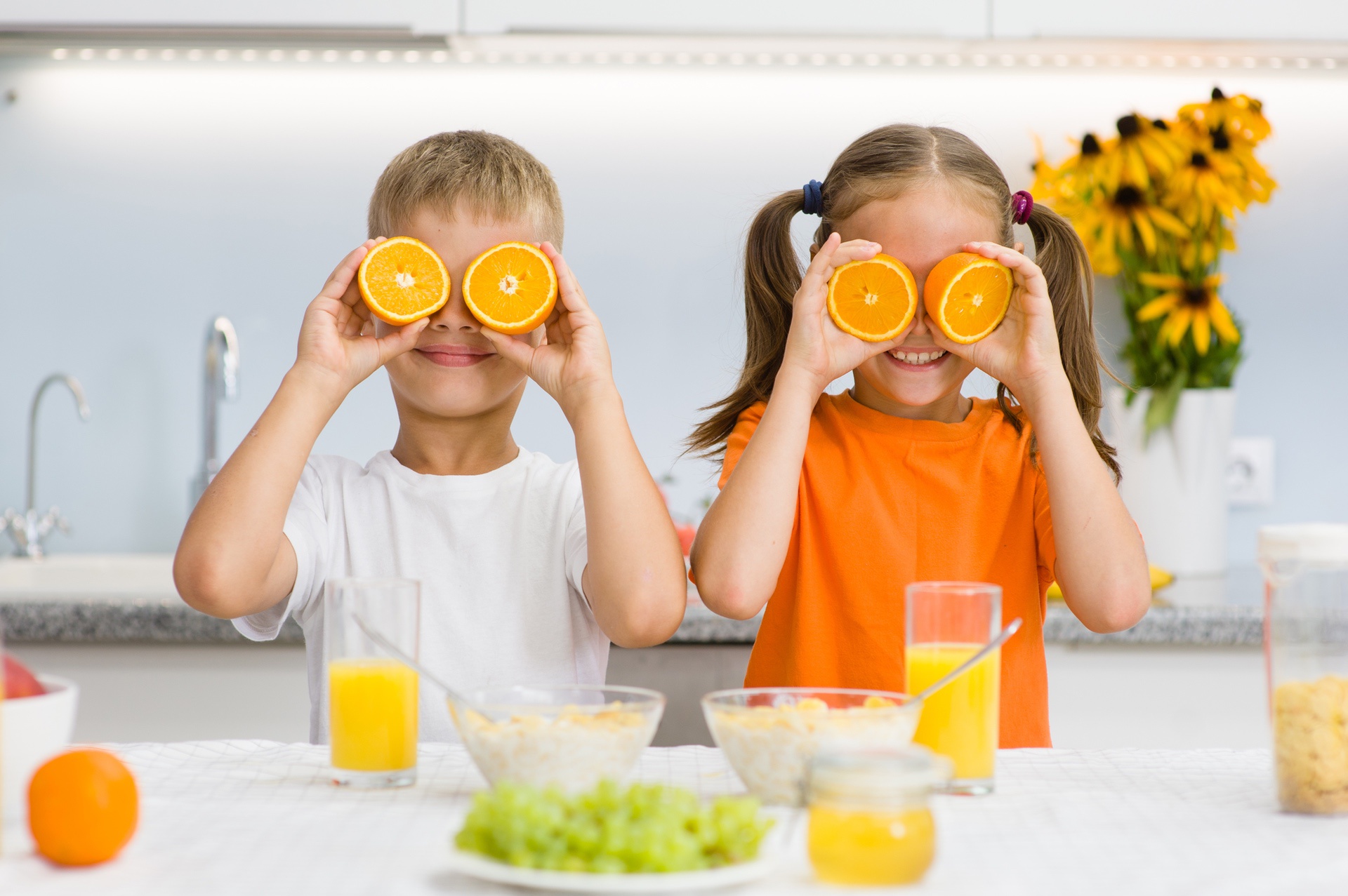Kids smiling and using oranges for eyes