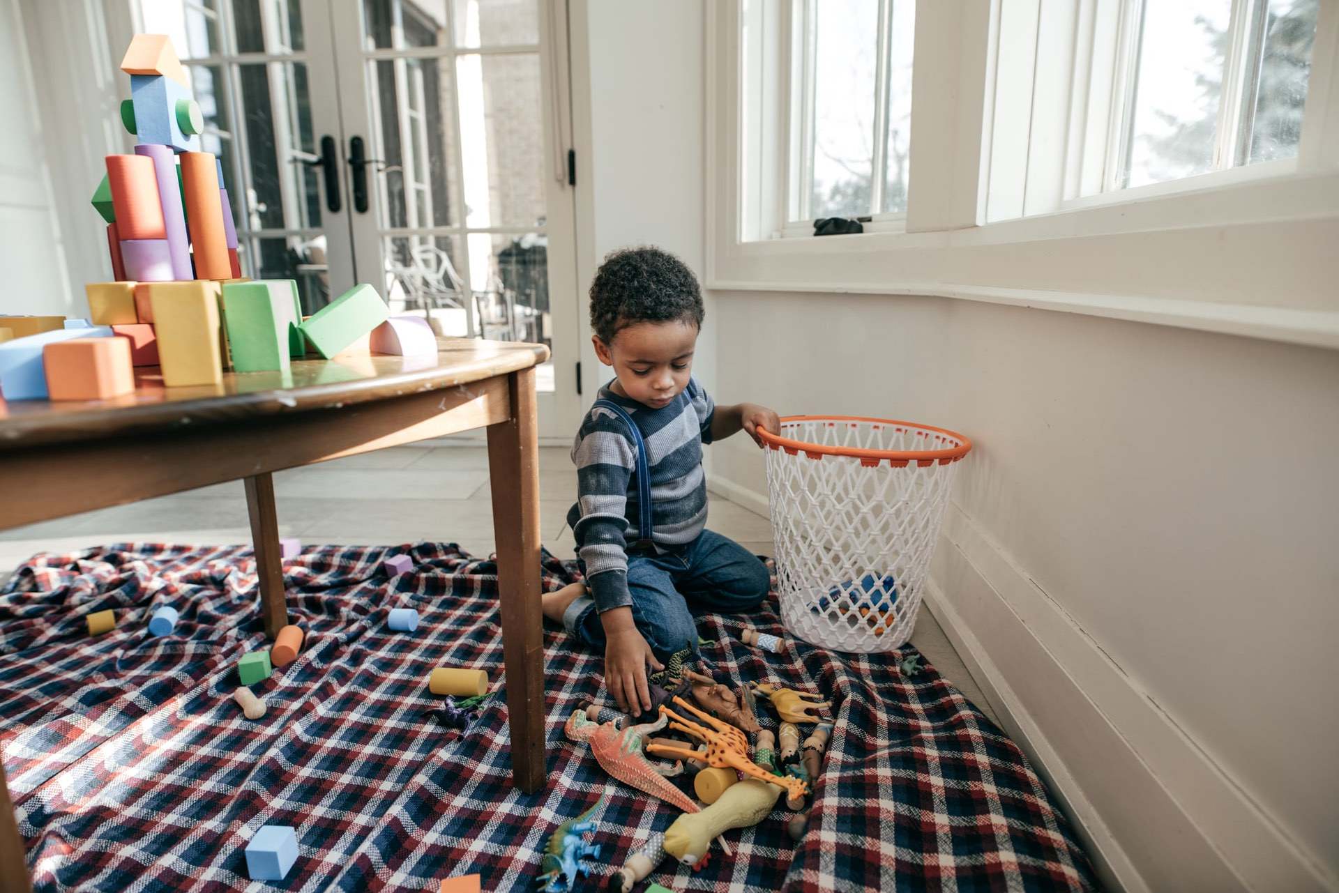 Child putting toys away in room